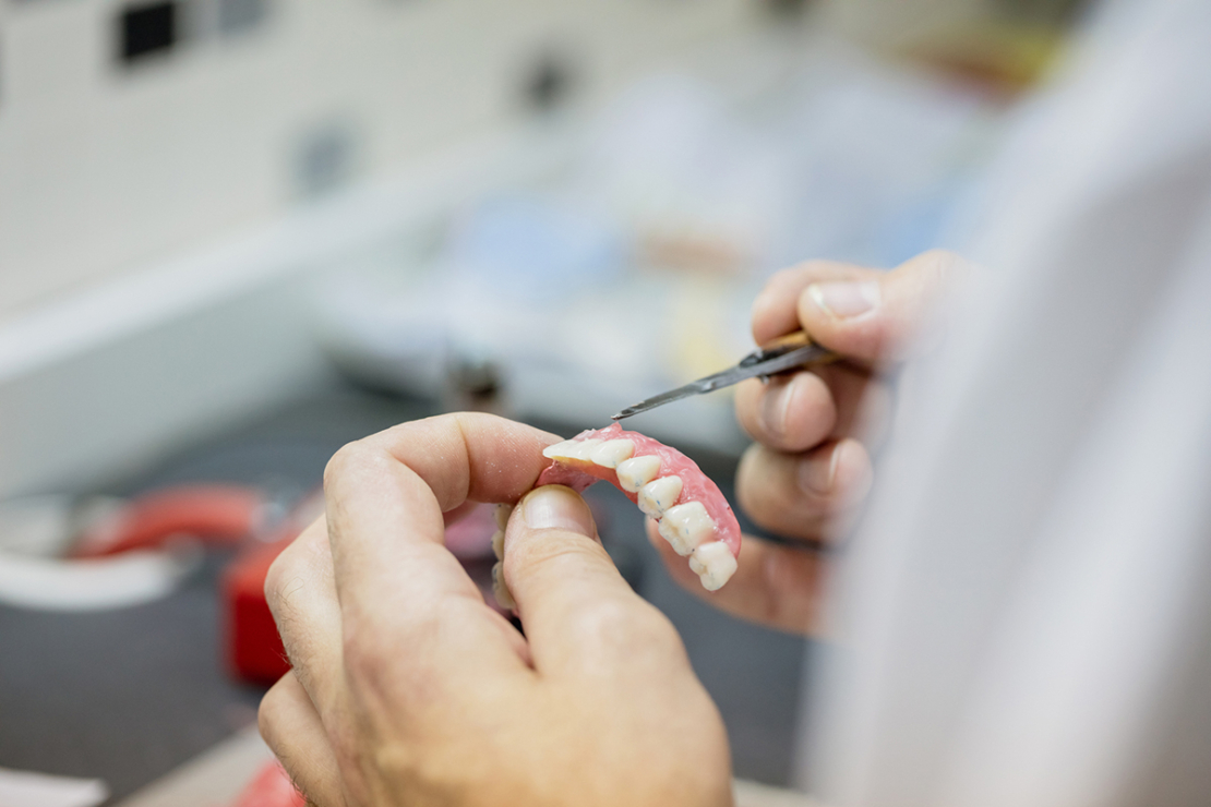 Dentist working on set of dentures image